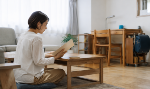 子どもの学習机があるリビングで資料を確認する女性