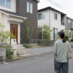 住宅街を歩きながら戸建ての外観を眺める女性の後ろ姿