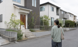 住宅街を歩きながら戸建ての外観を眺める女性の後ろ姿