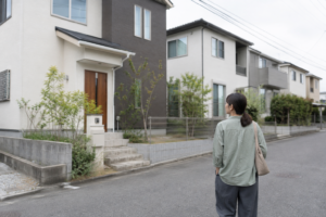 住宅街を歩きながら戸建ての外観を眺める女性の後ろ姿