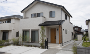 明るい曇り空の下に建つ一般的な二階建て住宅