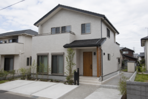 明るい曇り空の下に建つ一般的な二階建て住宅