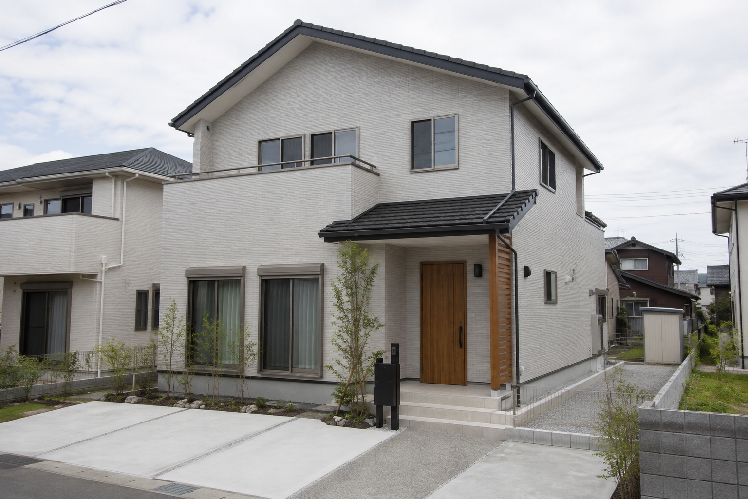 明るい曇り空の下に建つ一般的な二階建て住宅