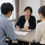 相談室のテーブルで相談員の説明を聞く二人