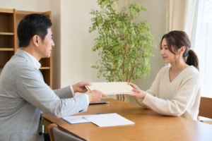 住宅相談の机で担当者から資料を受け取る女性