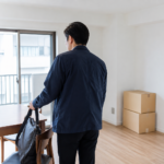 引っ越し後の部屋で仕事用のバッグを椅子に置く男性
