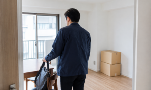 引っ越し後の部屋で仕事用のバッグを椅子に置く男性