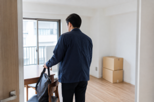 引っ越し後の部屋で仕事用のバッグを椅子に置く男性