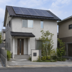 太陽光パネルを屋根に設置した戸建て住宅を道路から見た風景ｈ
