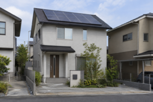 太陽光パネルを屋根に設置した戸建て住宅を道路から見た風景ｈ