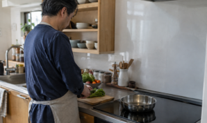 IHのあるキッチンで野菜を準備する男性の後ろ姿