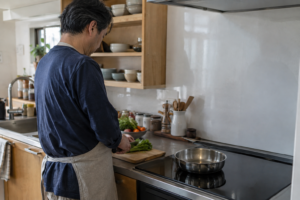 IHのあるキッチンで野菜を準備する男性の後ろ姿